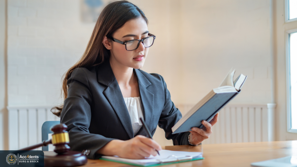 Lawyer reading a law book and taking notes at a desk with a gavel nearby