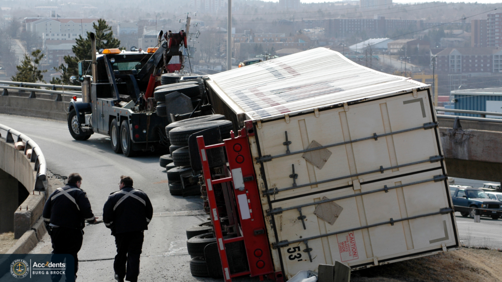 Overturned semi-truck being recovered on a highway ramp Overturned semi-truck trailer blocking a highway ramp while a heavy-duty tow truck and two recovery workers prepare to upright it